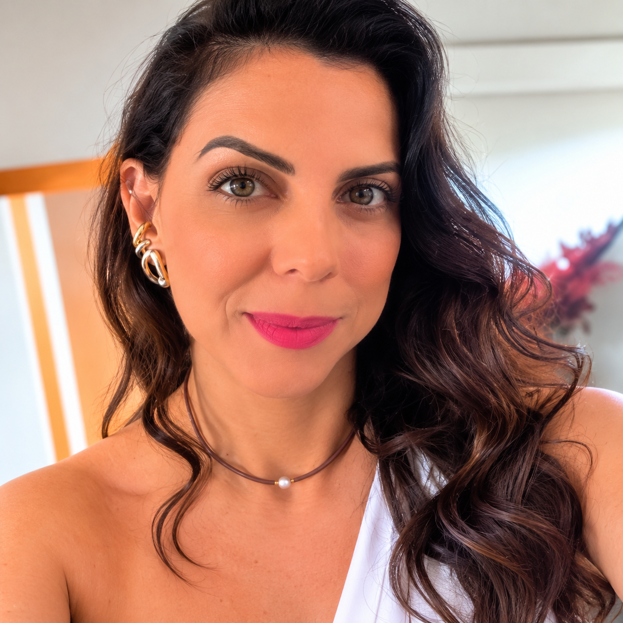 Denise, fundadora da Lavini Semijoias, usando brincos e colar dourados